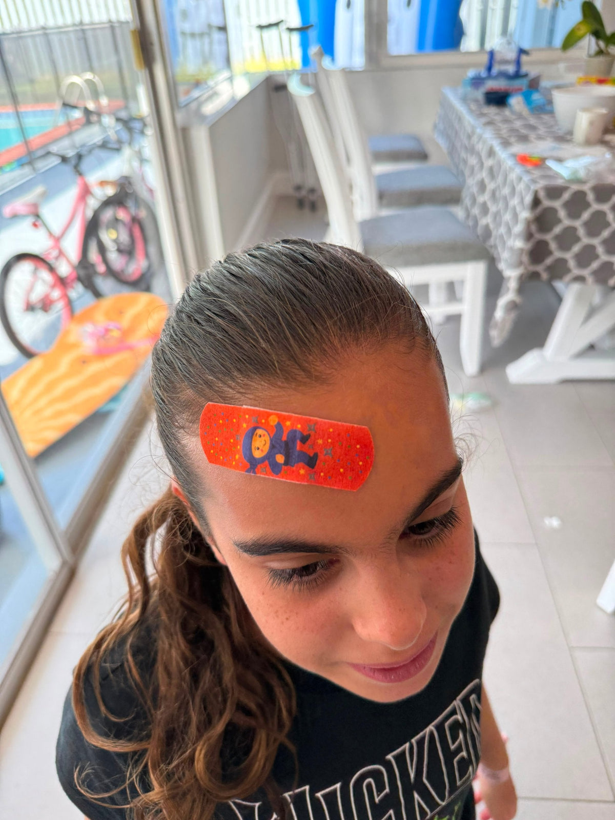 Close-up of a child’s forehead with a colorful orange BooBoo Cooler® bandage covering a bump, showing the common spot where kids bruise.